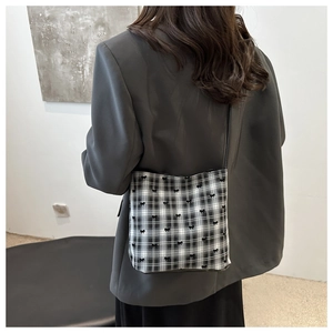 Chic black and white plaid crossbody bag with tiny bows styled on a grey casual blazer
