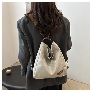 Detail view of large beige multifunctional denim backpack with leather side accents