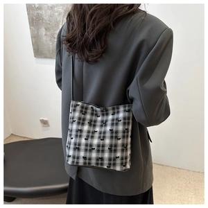 Detail of minimalist black and white checkered shoulder bag with 3D bow accents