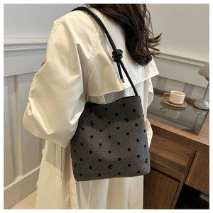 Detail of grey polka dot bucket bag with bow patterns and black knotted strap