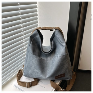 Close-up of blue denim tote bag featuring large front pockets and brown fabric straps