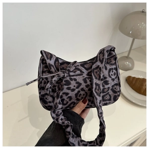 Close-up of leopard print underarm bag with fabric texture and decorative bow detail