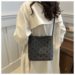 Gray bucket bag with black polka dots and bows shown on a model in a beige trench coat