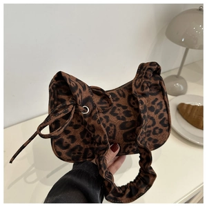 Close-up of leopard print shoulder bag featuring ruched handle and metal eyelet details