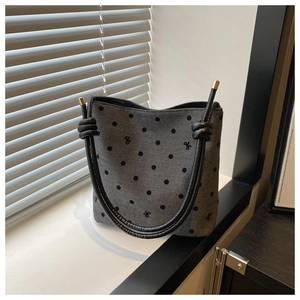 Close-up of grey bucket bag with black polka dots and butterfly embroidery details