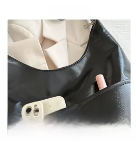 Detail shot of black faux leather shoulder bag with functional front pocket for phone
