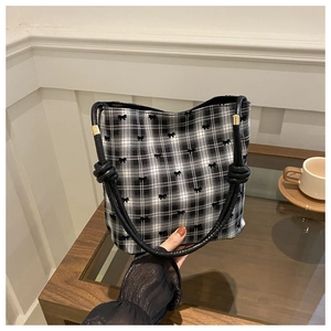 Detail of checkered bucket bag with mini bows, knotted rope handle and gold hardware