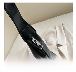 Detail of silver smooth zipper and reinforced stitching on black leather tote bag