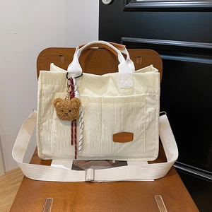 Chic corduroy tote bag in beige with bear charm on a wooden chair
