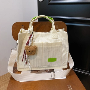 Minimalist corduroy tote bag in cream with green handles and a cute plush bear charm