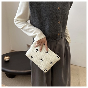 Close-up of white quilted cosmetic bag with delicate black bow embroidery detail