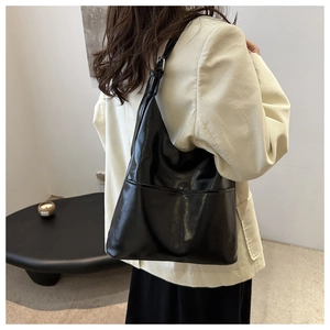 Detail of black patent leather tote bag with pocket design on beige corduroy blazer