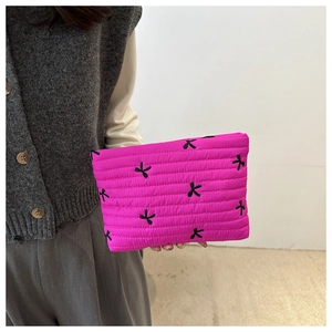 Detail of rose red quilted cosmetic bag with black bow embroidery and puffy texture