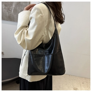 Detail of black leather hobo tote bag featuring functional front pockets and soft texture
