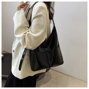 Detail view of the black glossy leather tote bag with an adjustable shoulder strap and pocket