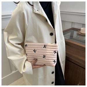 Detail of pink quilted makeup bag with black bow embroidery and striped texture
