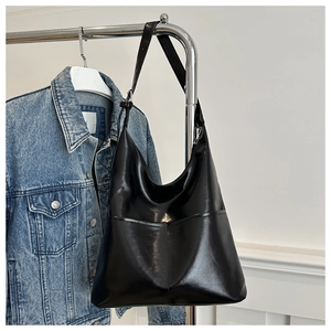 Detail of glossy black faux leather tote bag with dual front pockets on metal stand