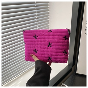 Detail of rose red quilted pouch featuring black bow embroidery and secure zipper closure