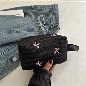 Quilted black makeup bag with pink bow embroidery and convenient side handle