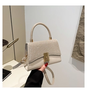 Dettaglio borsa a tracolla avorio glitterata con chiusura dorata e texture scintillante