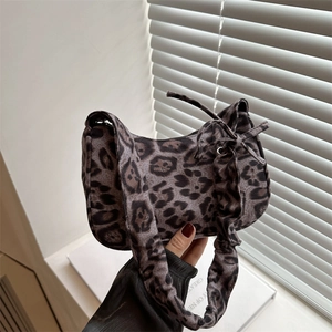 Retro leopard print underarm bag with scrunchie strap and bow detail on a sunny window