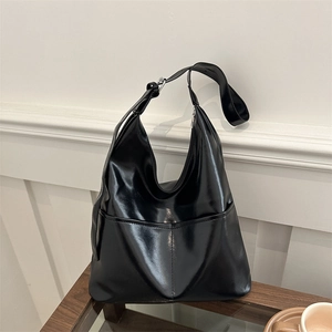 Minimalist black tote bag in glossy faux leather featuring wide shoulder straps and pockets