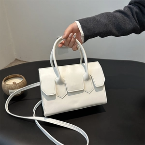 Minimalist white faux leather handbag with top handles and shoulder strap on a black stand