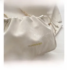 Detailed close-up of marble pattern cream cloud bag with gold chain strap and branding