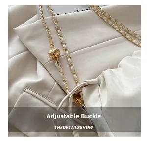 Detail of cream chain bag with adjustable gold buckle and pleated texture design
