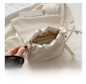 Interior capacity detail of beige pleated bucket bag with chain strap and magnetic closure