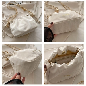 Detail of off-white pleated cloud bag with gold chain and adjustable metal bead strap