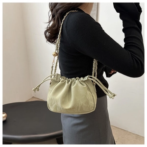 Detail of light green drawstring bucket bag with gold chain strap and metal ball adjuster