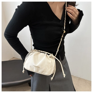 Detail of white pleated cloud bag featuring golden chain strap and decorative text