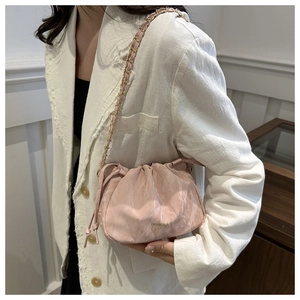 Detail view of light pink pleated bucket bag with gold chain strap and textured marble finish