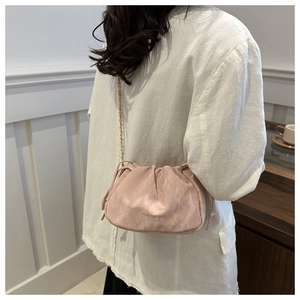 Detail of pale pink bucket bag with drawstring folds and fine gold chain strap