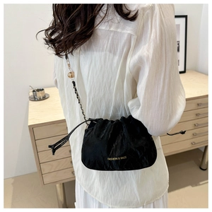 Detail of black drawstring bag featuring a gold chain strap and spherical pendant charm