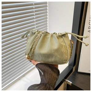 Detail of light green bucket bag with gold chain strap and marble texture finish