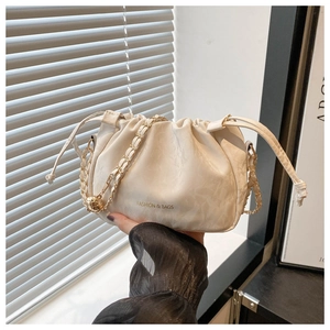 Detail of a creamy white cloud bag featuring gold chain strap and drawstring closure