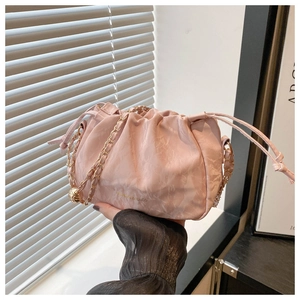 Close-up of light pink textured cloud bag with gold chain and drawstring detail