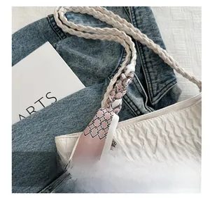 Gros plan du sac froncé blanc avec bandoulière tressée et détail de foulard en soie rose