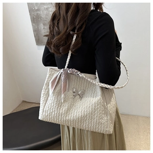 Détail du sac froissé avec poignée tressée, foulard en soie et décoration papillon argenté