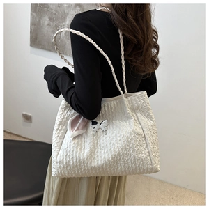 Détail du sac nuage plissé blanc avec anses tressées et un pendentif papillon élégant