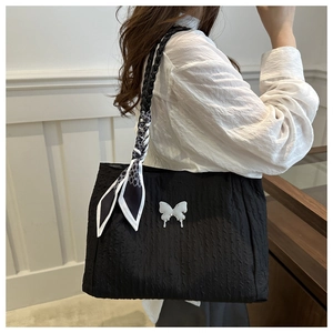 Détail du sac fourre-tout plissé noir avec breloque papillon blanc et foulard en soie