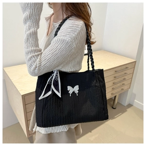 Détail d'un sac cabas plissé noir avec papillon argenté et foulard décoratif
