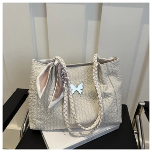 Détail du sac froissé avec poignée tressée, papillon argenté et foulard en soie rose