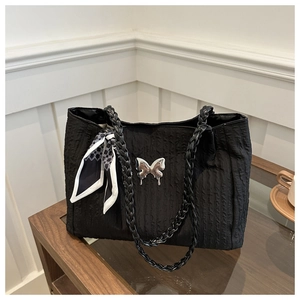 Détail du cabas plissé noir avec pendentif papillon et foulard géométrique en soie