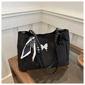 Détail du sac cabas plissé noir avec foulard en soie et breloque papillon sur bois