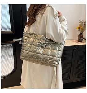 Close-up of champagne gold quilted tote bag with metallic chain and deer charm detail