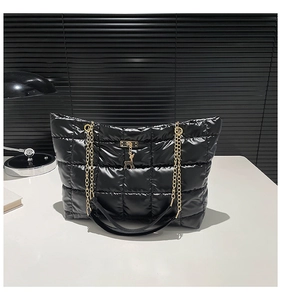 Detail of black quilted puffer tote with golden deer pendant and chain strap
