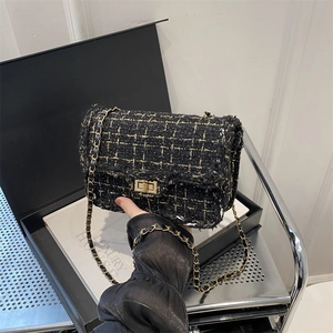 Elegant black and gold tweed crossbody bag with metal chain strap and turn-lock closure